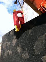 High Country Plastics Grabbit mat mover gripping the edge of a heavy rubber stall mat